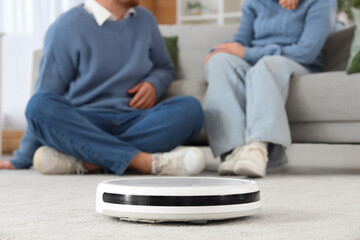 Robot vacuum cleaner and family at home, closeup
