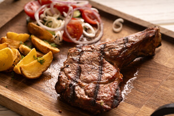 Barbecue grilled lamb chops serving with potatoes and tomatoes cherry on wooden board