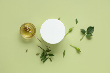 Jar of natural face cream and honey on green background