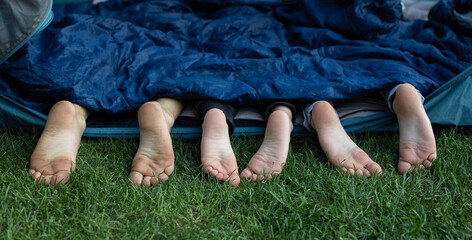 three pairs of cute bare feet of children sticking out of sleeping bag. Children, siblings or...
