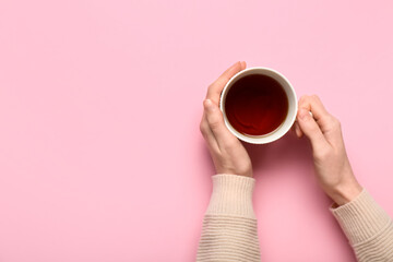 Female hands holding cup of black tea on color background