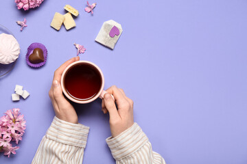 Woman holding cup of tea, tea bag and hyacinth on color background
