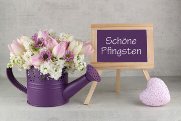 Grußkarte zu Pfingsten: Blumenstrauß mit Herz und dem Text schöne Pfingsten auf einer Schreibtafel.	