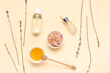 Sea salt, bottles of floral and honey essential oil on beige background