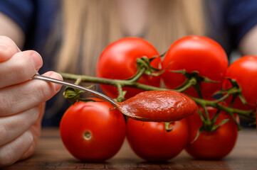 Zdrowy domowy ketchup, przecier pomidorowy na łyżeczce obok świeże pomidory - obrazy, fototapety, plakaty