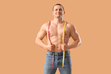 Male bodybuilder with measuring tapes on beige background
