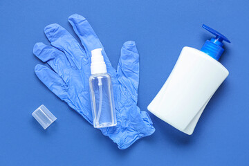 Rubber gloves with bottles of sanitizers on blue background