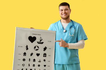 Male ophthalmologist pointing at eye test chart on yellow background