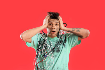 Electrocuted young man with burnt face and wires on red background