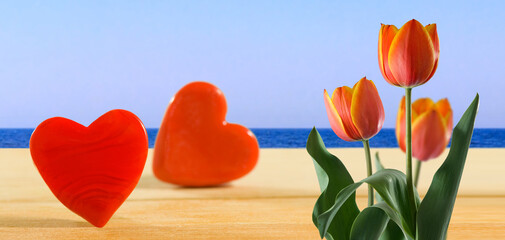 decorative hearts on a wooden surface and three beautiful red tulips