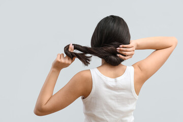 Beautiful young woman with healthy long hair on grey background, back view