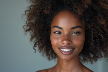 Close-up portrait of a young woman with curly hair and a bright smile