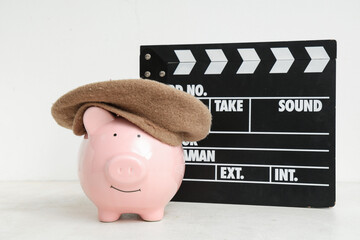 Piggy bank in beret with clapperboard on white background