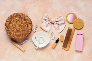 Beautiful composition of silk bow, wicker bag and accessories on pink grunge background