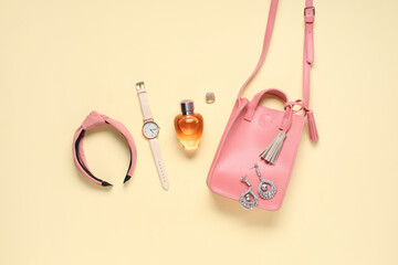 Hair hoop, pink bag and bottle of perfume on beige background