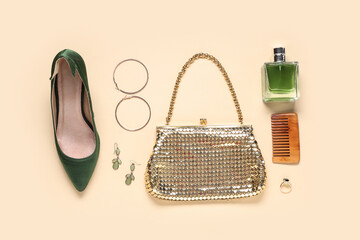 Golden bag, bottle of perfume and different woman's accessories on beige background
