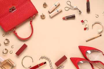 Frame made of red bag, lipsticks and beautiful jewellery on beige background