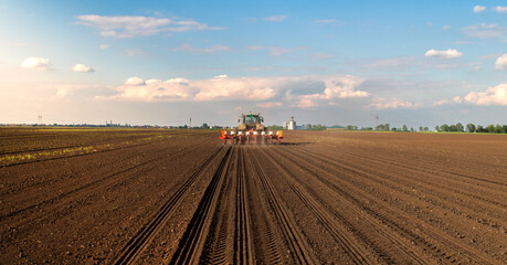 Farmer with tractor seeding in sunset