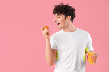Handsome young happy sporty man with glass of juice and orange on pink background. Weight loss...