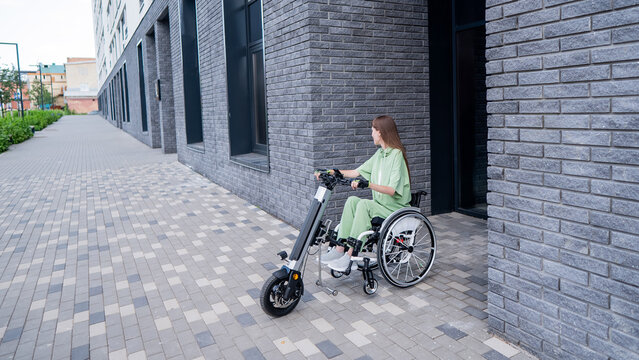 A woman in a wheelchair with an assistive device for manual control. Electric handbike. 