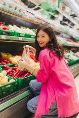 Young Korean woman shopping without plastic bags in grocery store. Vegan zero waste girl choosing fresh fruits and vegetables in supermarket. Part of a series