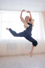Caucasian woman dances contemporary in ballet class. Dancer in a jump. Vertical photo.