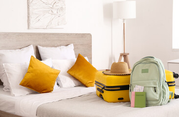 Suitcase, hat, backpack and passports with tickets on bed in hotel room