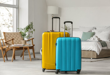 Interior of light hotel room with suitcases near bed