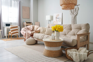 Cozy sofa and coffee table with bouquet of narcissus flowers in beautiful living room