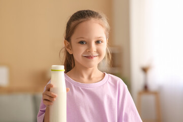 Cute little girl with bottle of yogurt at home