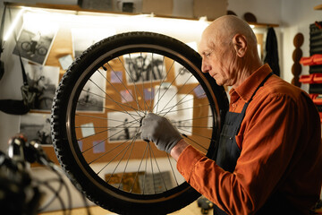 Bicycle repair in workshop, old man holding bike wheel