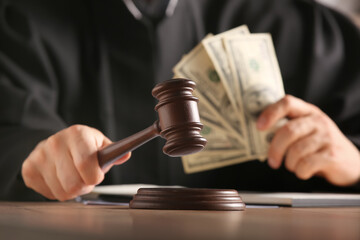 Male judge with gavel and money at table in office