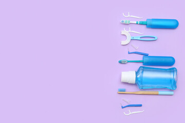 Toothbrushes with floss toothpicks and mouthwash on lilac background