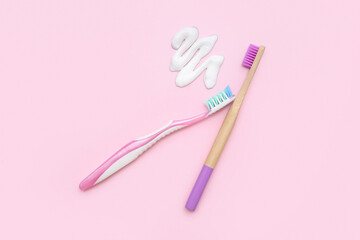 Toothbrushes with sample of toothpaste on pink background