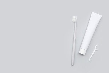 Toothpaste with toothbrush and floss toothpick on grey background