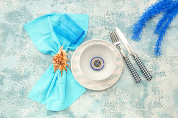 Beautiful table setting with seashell and compass on blue grunge background