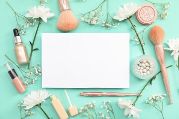 Composition with blank paper sheet, flowers and decorative cosmetics on green background