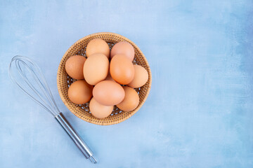 Top view of organic chicken eggs in basket on wooden background.