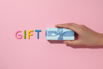 The word "gift" is made of colored plasticine, laid out on a pink background.
