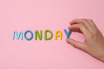 The word "Monday" is made of colored plasticine, laid out on a pink background.
