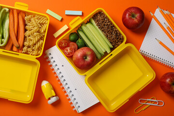 Yellow lunch box with delicious food and school supplies