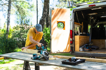 Man cutting wooden slats to customize his camper van