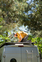 Middle aged man fixing the roof of a camper van outdoors