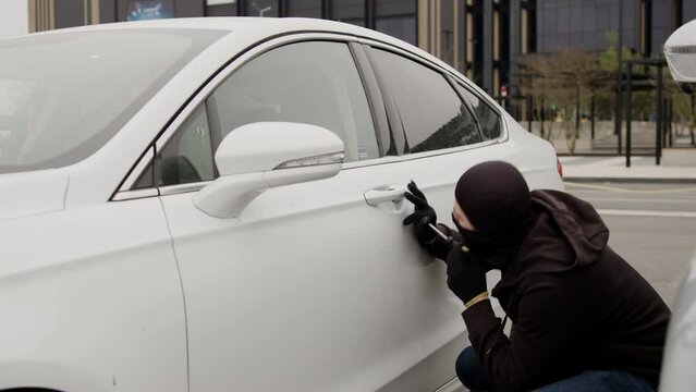 Criminal thief breaches car's defenses successfully breaking in without alerting anyone nearby. Criminal mastermind swiftly bypasses car's security measures executing theft undetected leaving.