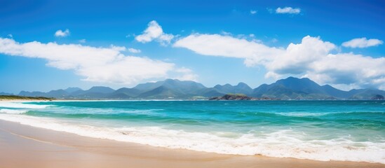 View of beach with distant mountain backdrop - obrazy, fototapety, plakaty
