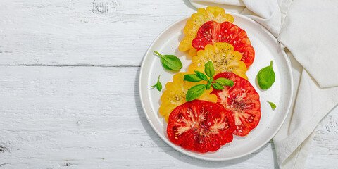 Colorful Heirloom tomato harvest. Ripe ribbed vegetables with fresh basil leaves. Wooden background