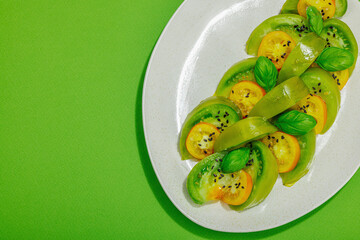 Fresh summer salad from green heirloom tomato Kiwi, fresh basil leaves and extra virgin olive oil