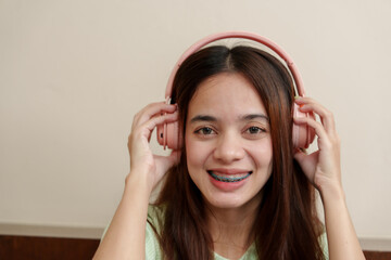 Engrossed in audio bliss, female with headphones over ears, eyes twinkling, exhibits a subtle,...