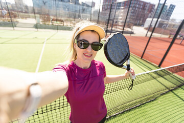 Active young woman trying to beat the ball by Padel racket while playing tennis in the court - 796327295