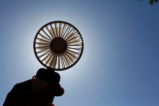 Hand holding a portable rechargeable electric fan
